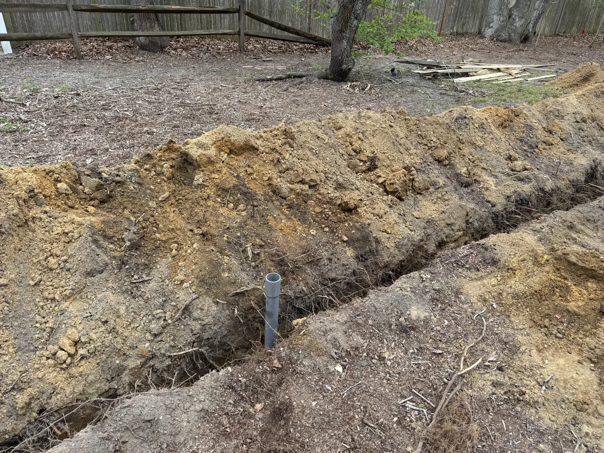A muddy streambank with eroded soil, gravel, and a small gray marker post.