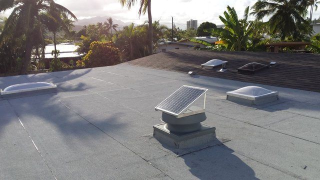 A roof with two skylights and a solar panel on it.