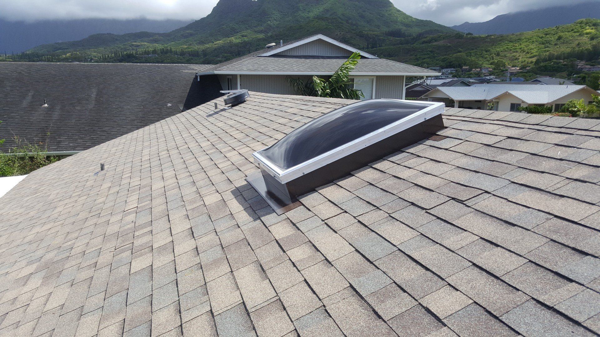A roof with a skylight and mountains in the background.