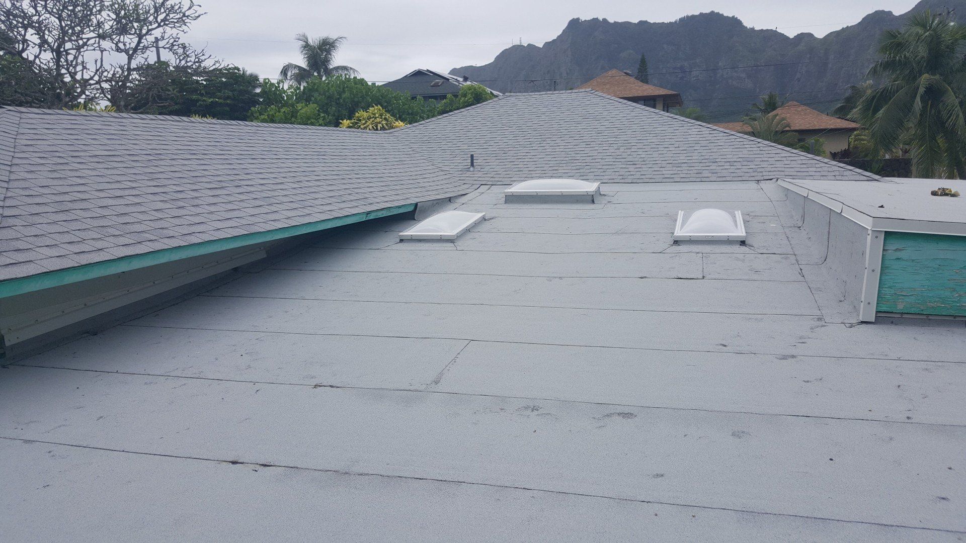 A roof with two skylights on it and mountains in the background.