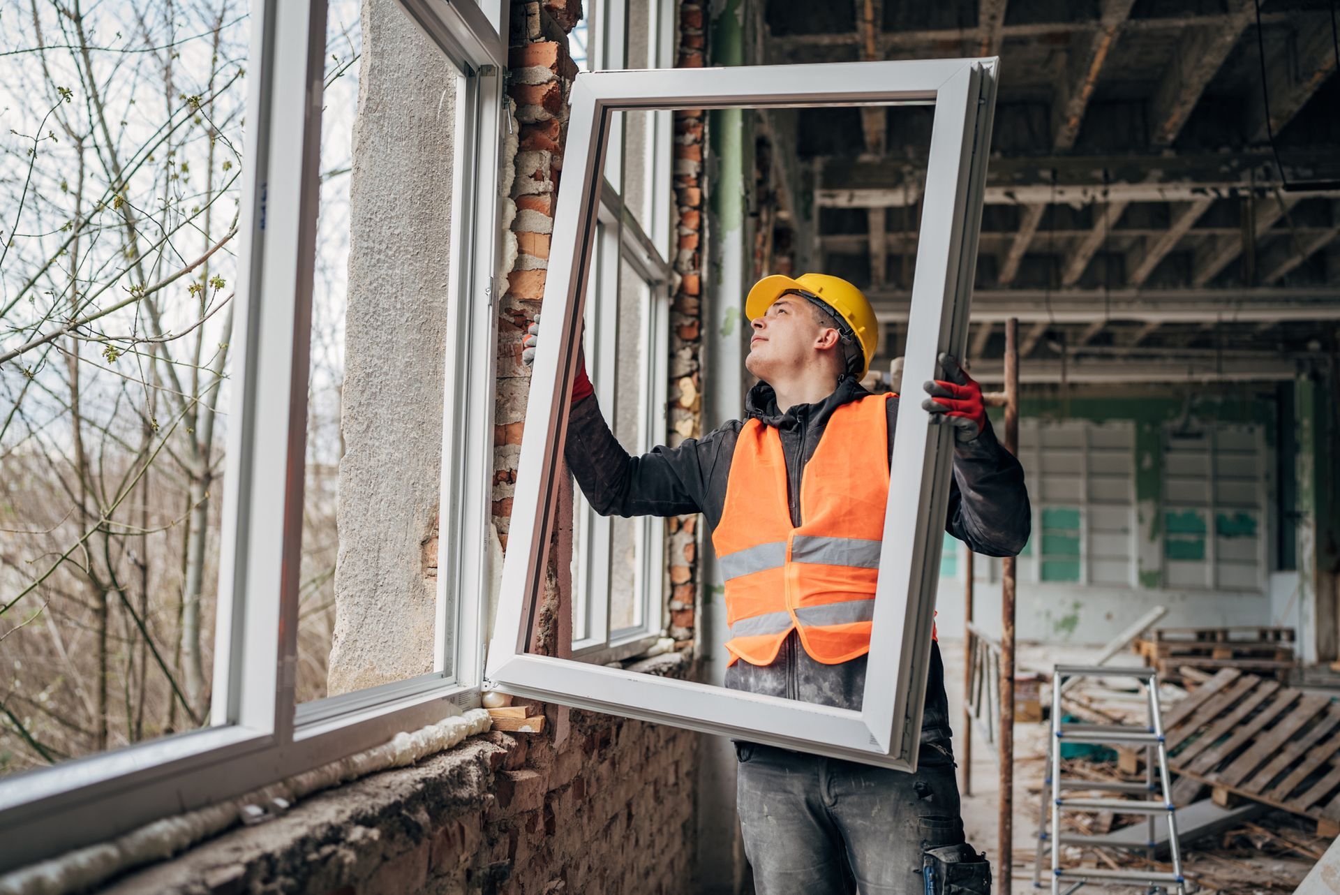 Two men wearing hard hats are installing a window.