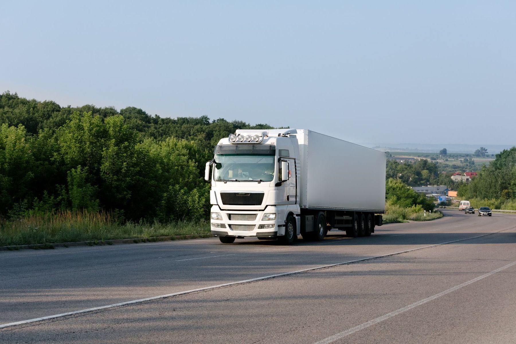 A white semi truck is driving down a highway.