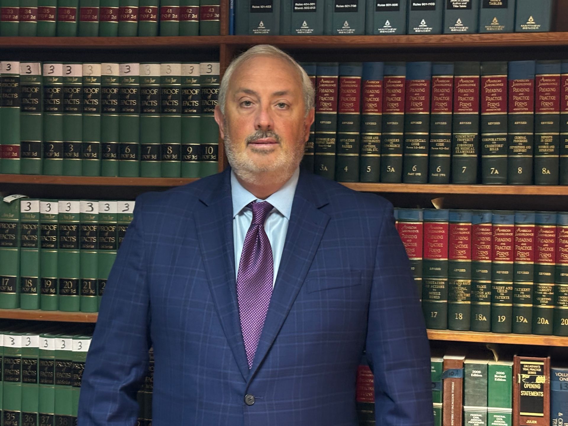 Man in a blue suit standing in front of shelves of law books