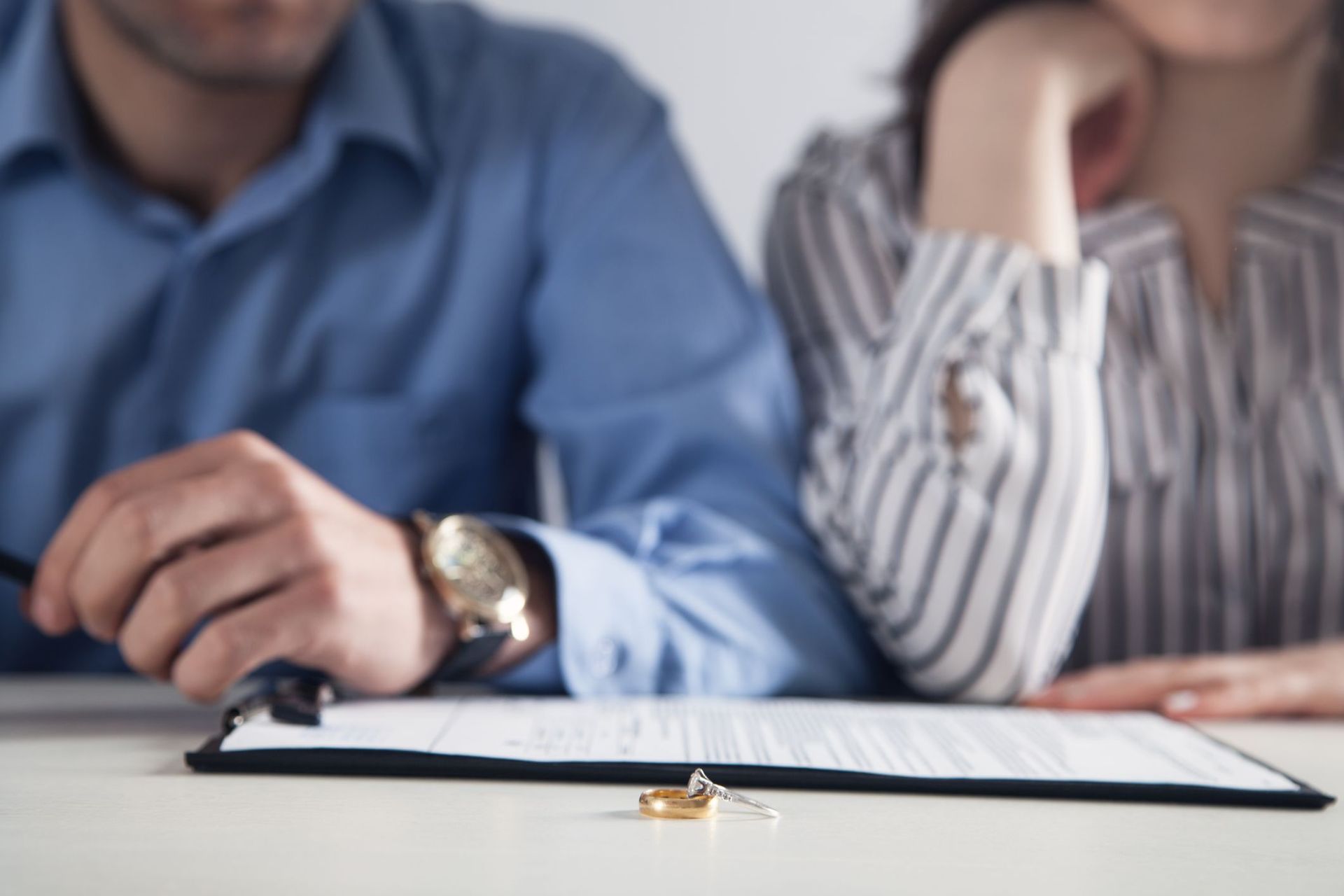 Couple signing a document at a table with a small ring in the foreground