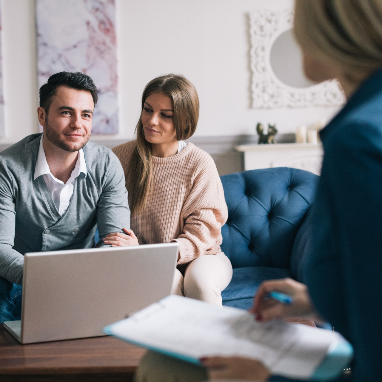 Two people meeting with a counselor in a bright office, laptop and notebook visible