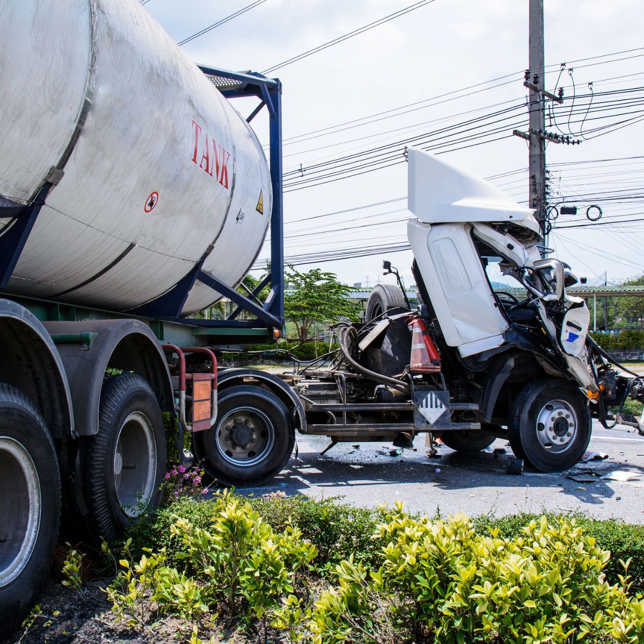 Two trucks collided on a road, one white cab crushed under a tanker trailer.