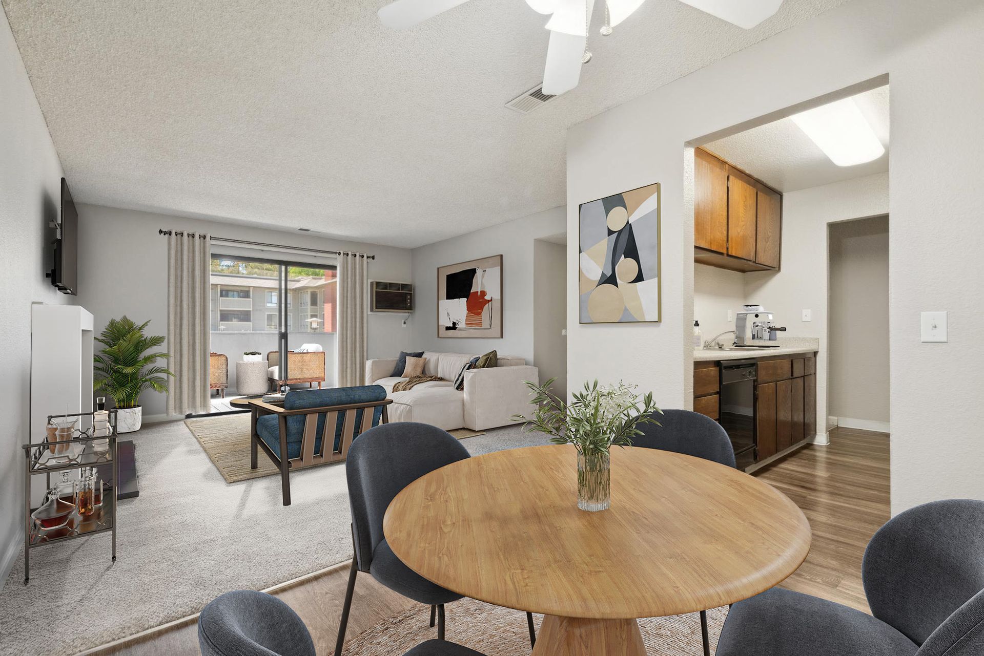 Open-concept apartment living area with round wooden dining table, sofa, and visible kitchen at Muirwood apartments in Martinez, CA.