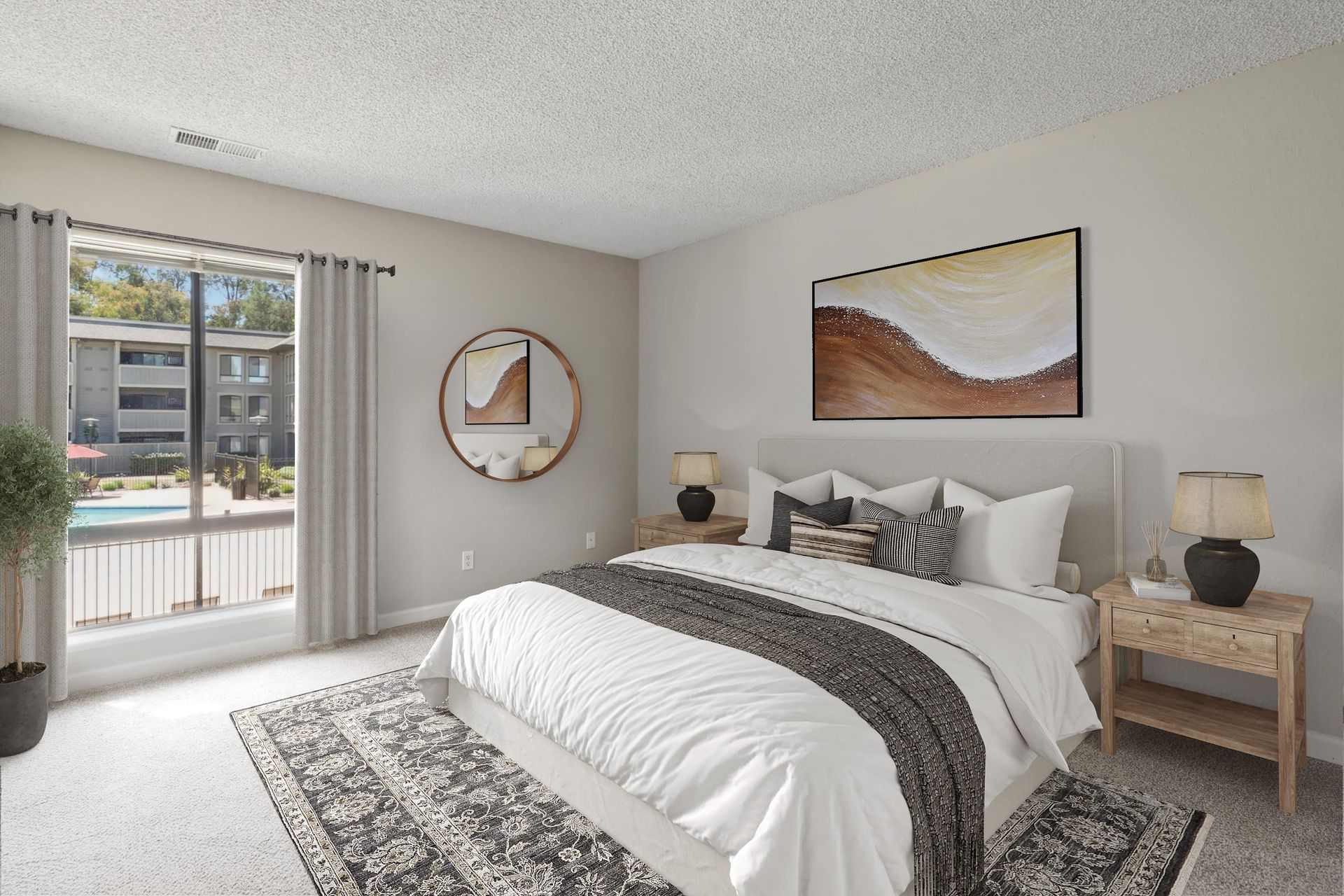 Bedroom in an apartment with a bed, two nightstands, lamps, wall art, and a pool view through a large window at Muirwood apartments in Martinez, CA.