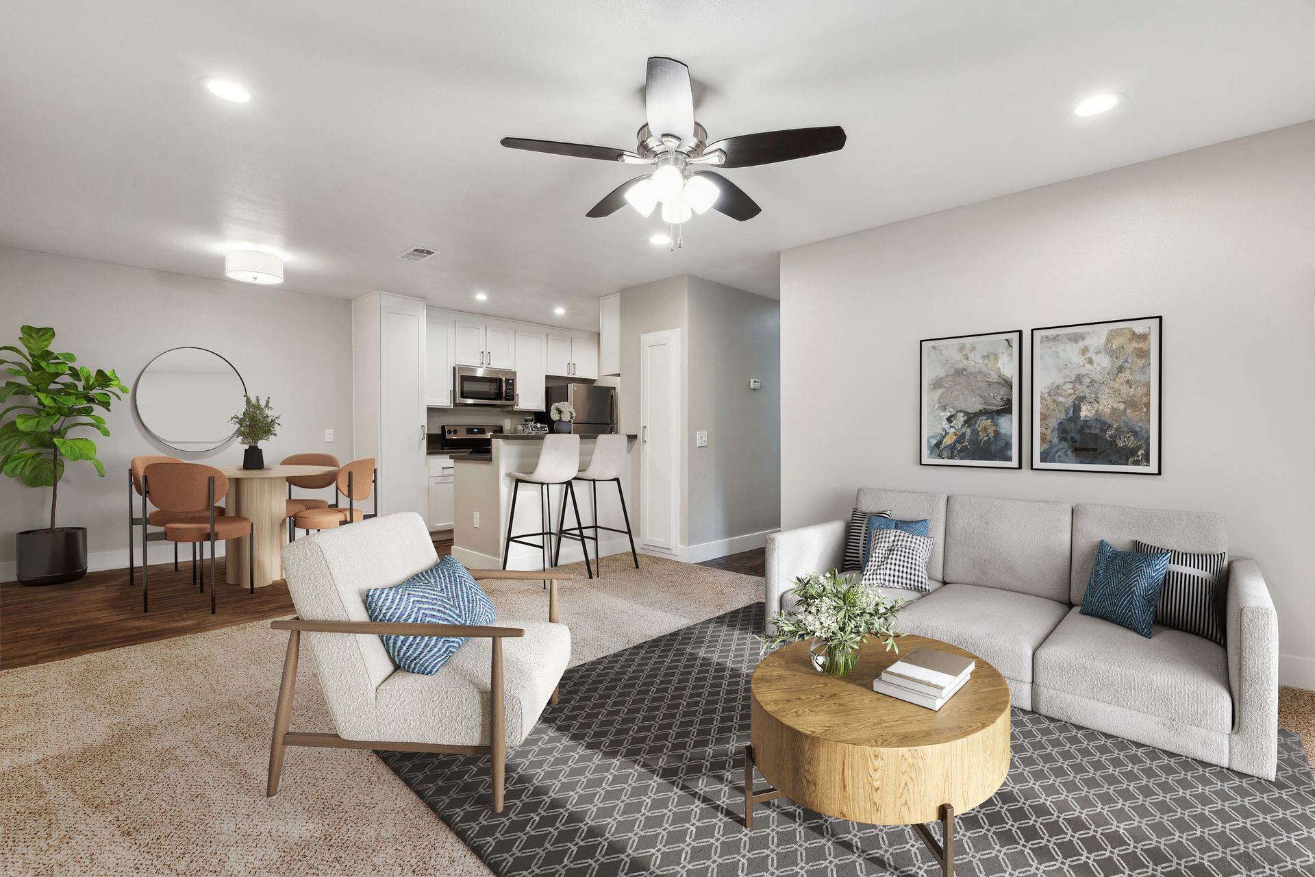Open-concept living room with sofa, armchair, round coffee table, dining area, and kitchen in the background at Muirwood apartments in Martinez, CA.