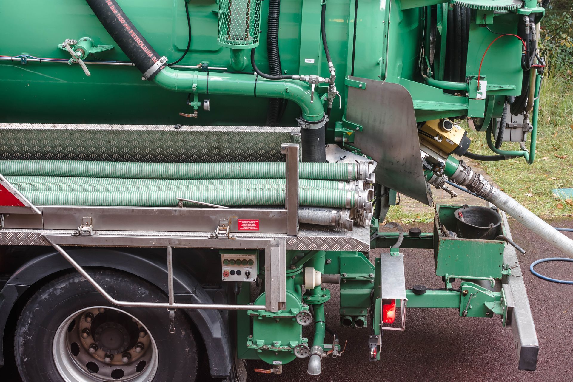 A green vacuum truck is parked on the side of the road