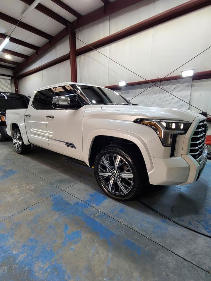 White Toyota Tundra pickup truck inside a workshop with shiny chrome wheels.