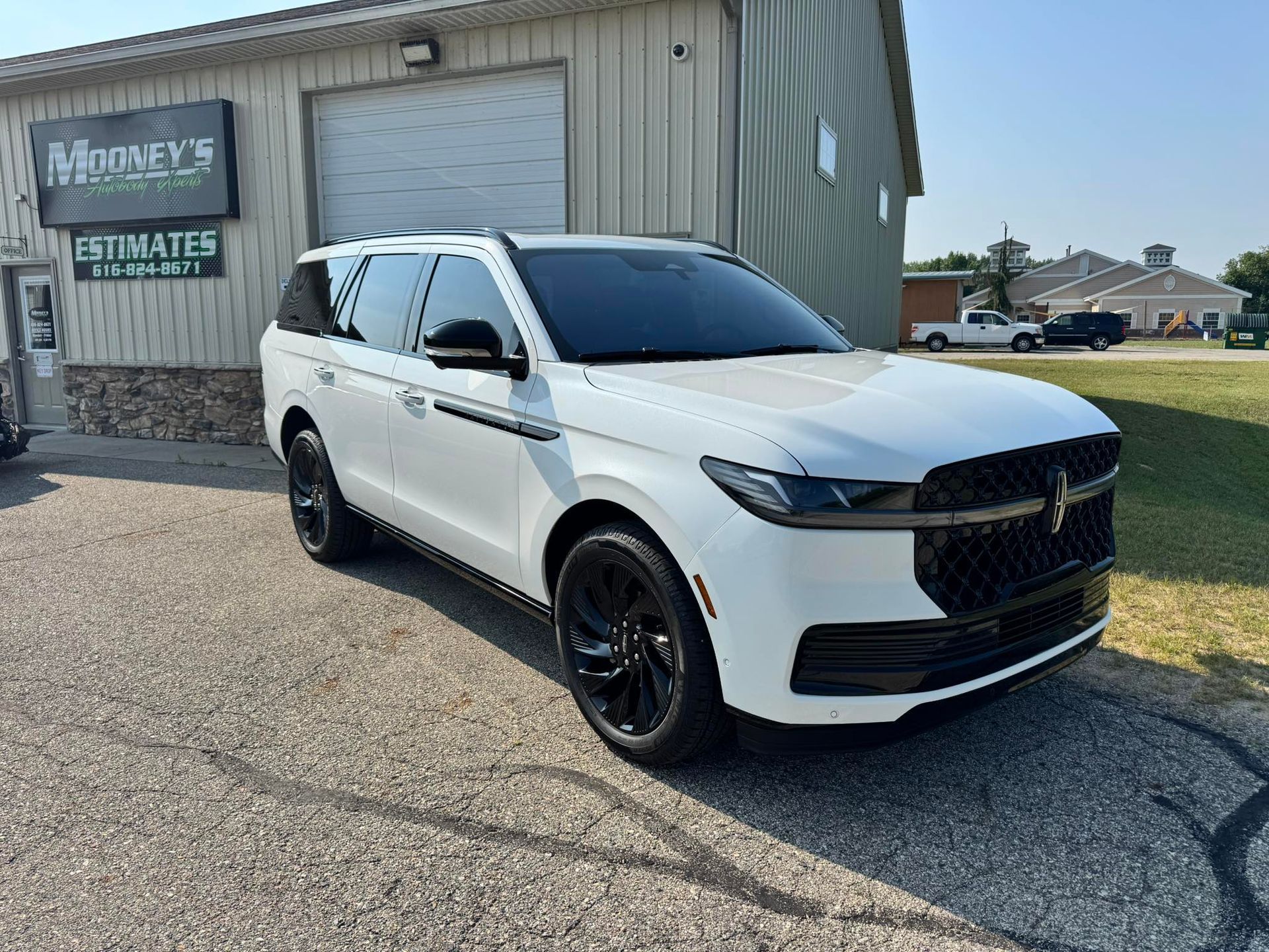 A white full-size SUV with black trim and wheels parked on an asphalt lot in front of a building.