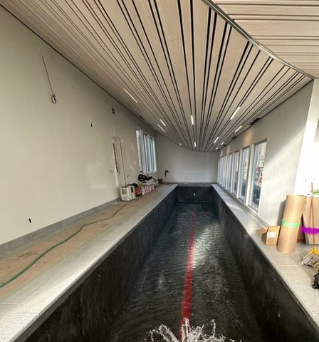 Indoor canal-like pool under construction with white ceiling slats