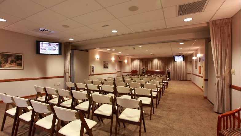 a funeral home with rows of green chairs and a television on the wall .