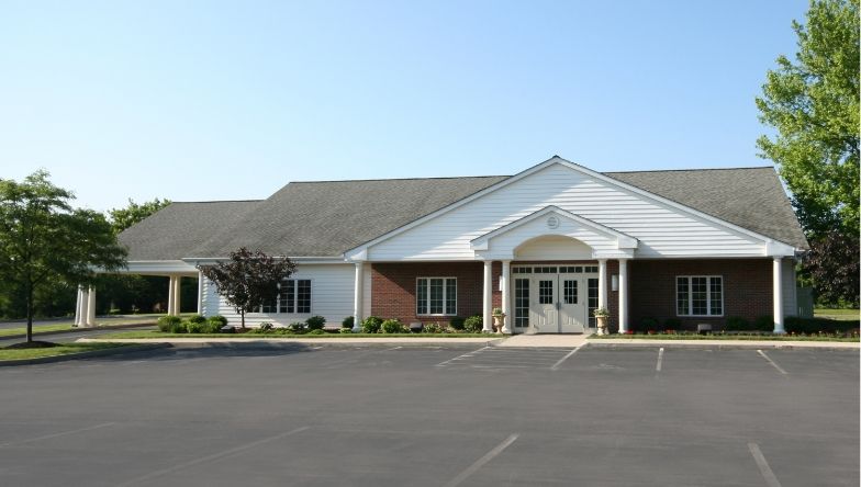A large white building with a brick facade and a parking lot in front of it