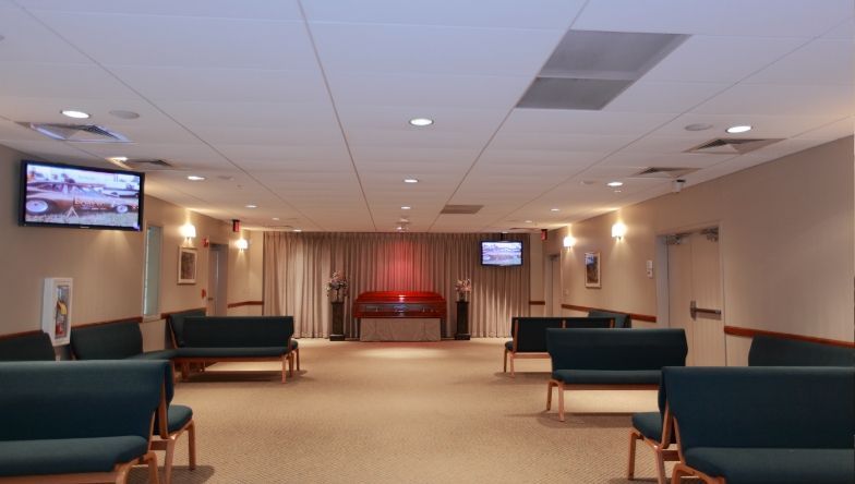 a funeral home with a coffin and two televisions on the wall .
