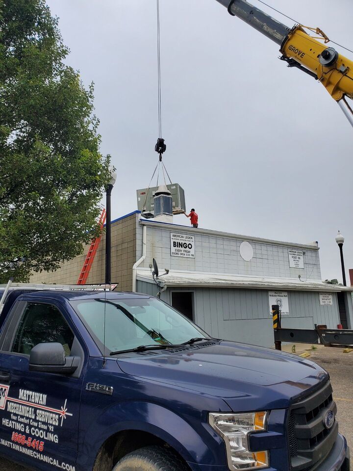 A truck is being lifted by a crane on top of a building.