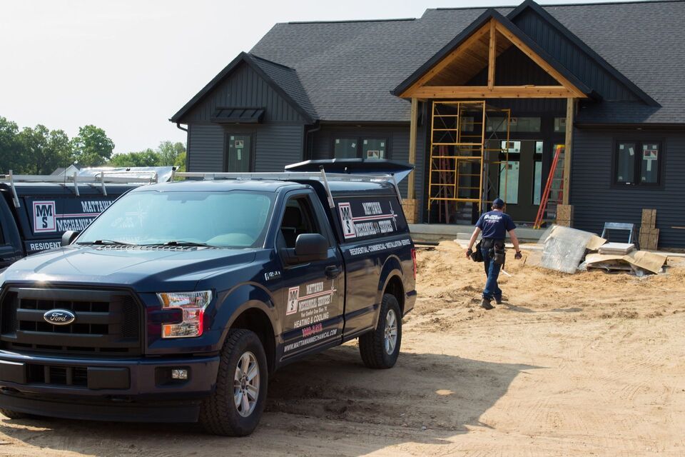 A ford truck is parked in front of a house under construction.