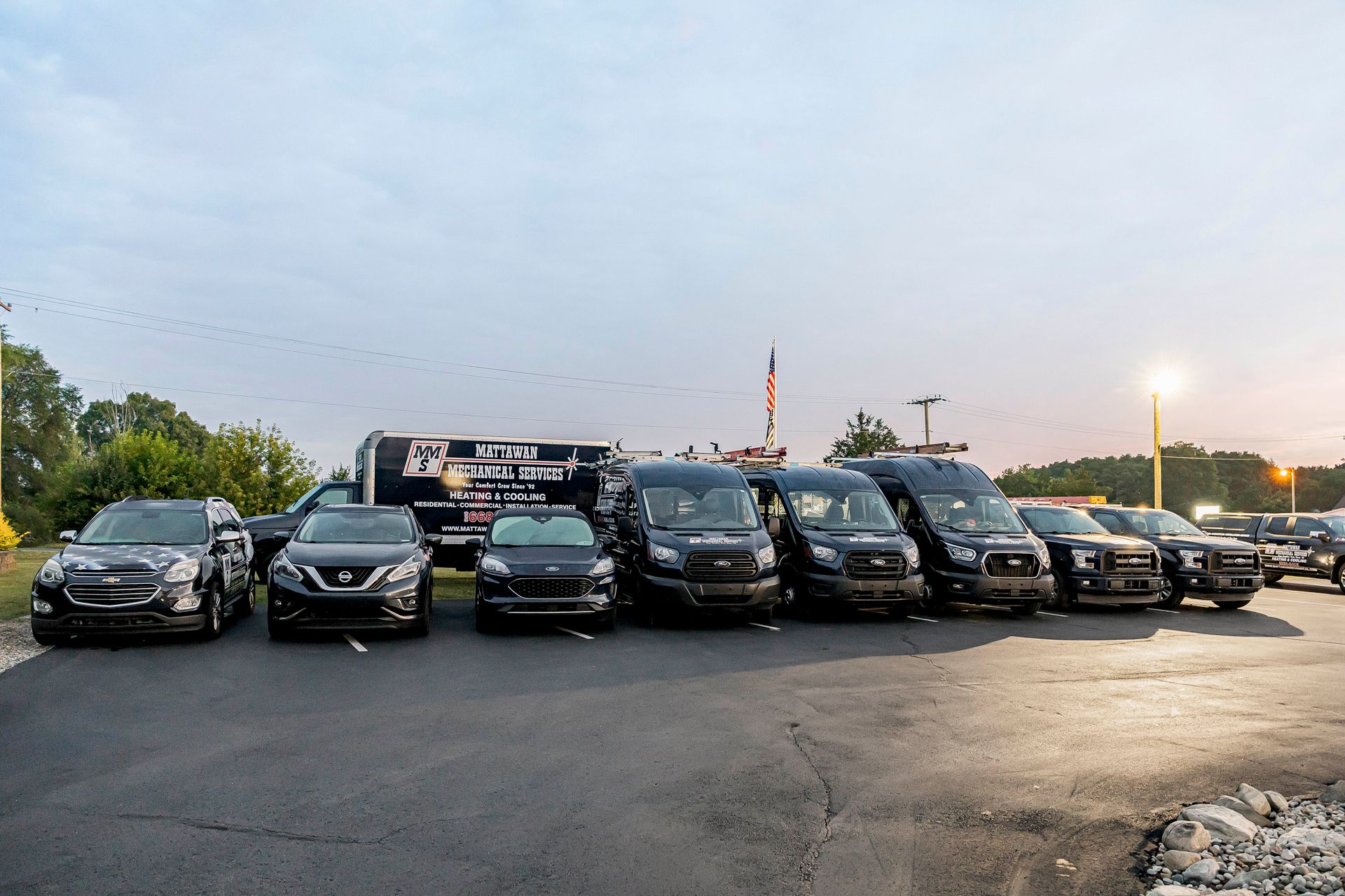 A row of black cars are parked in a parking lot