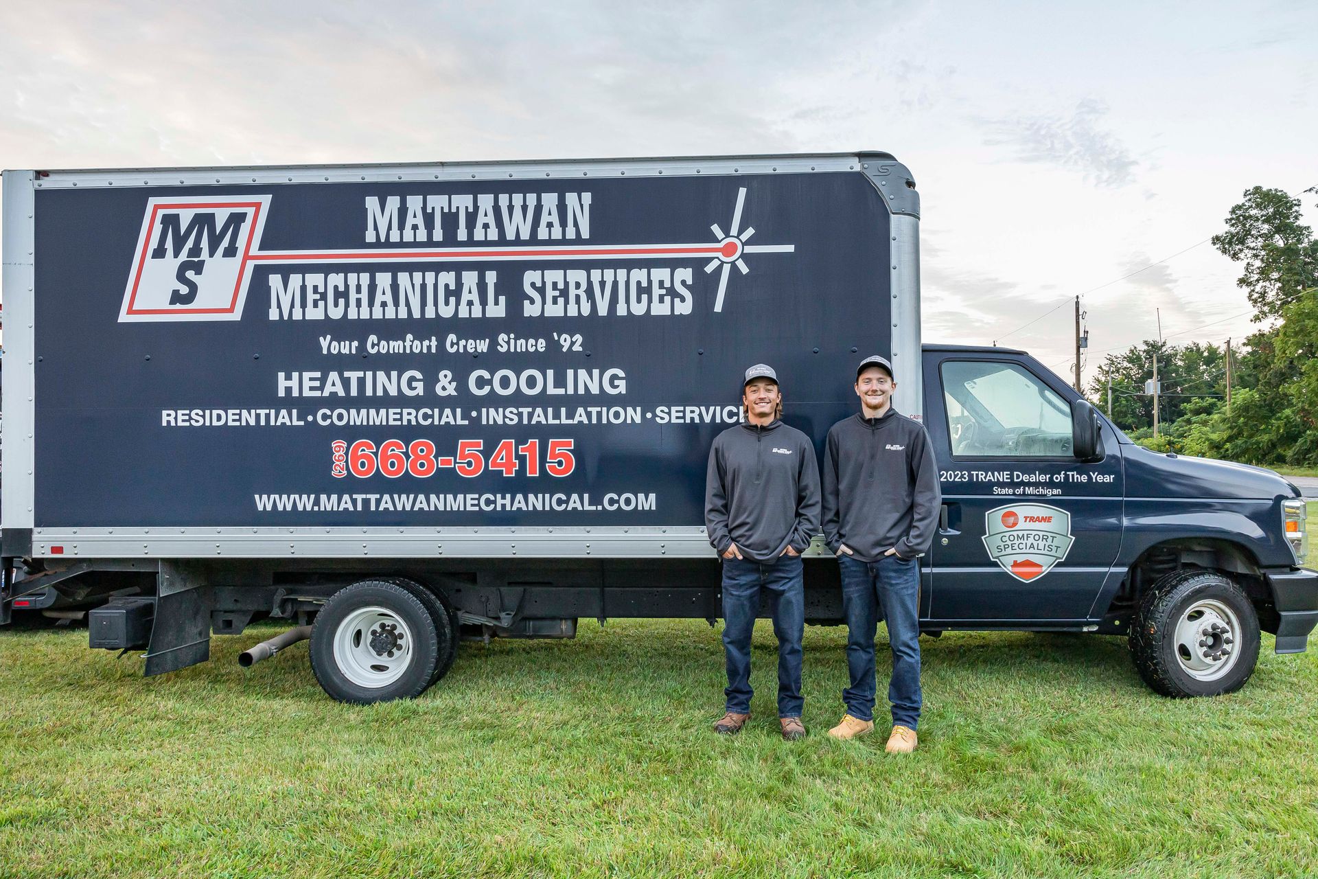 Two men standing in front of a truck that says mattawan mechanical services