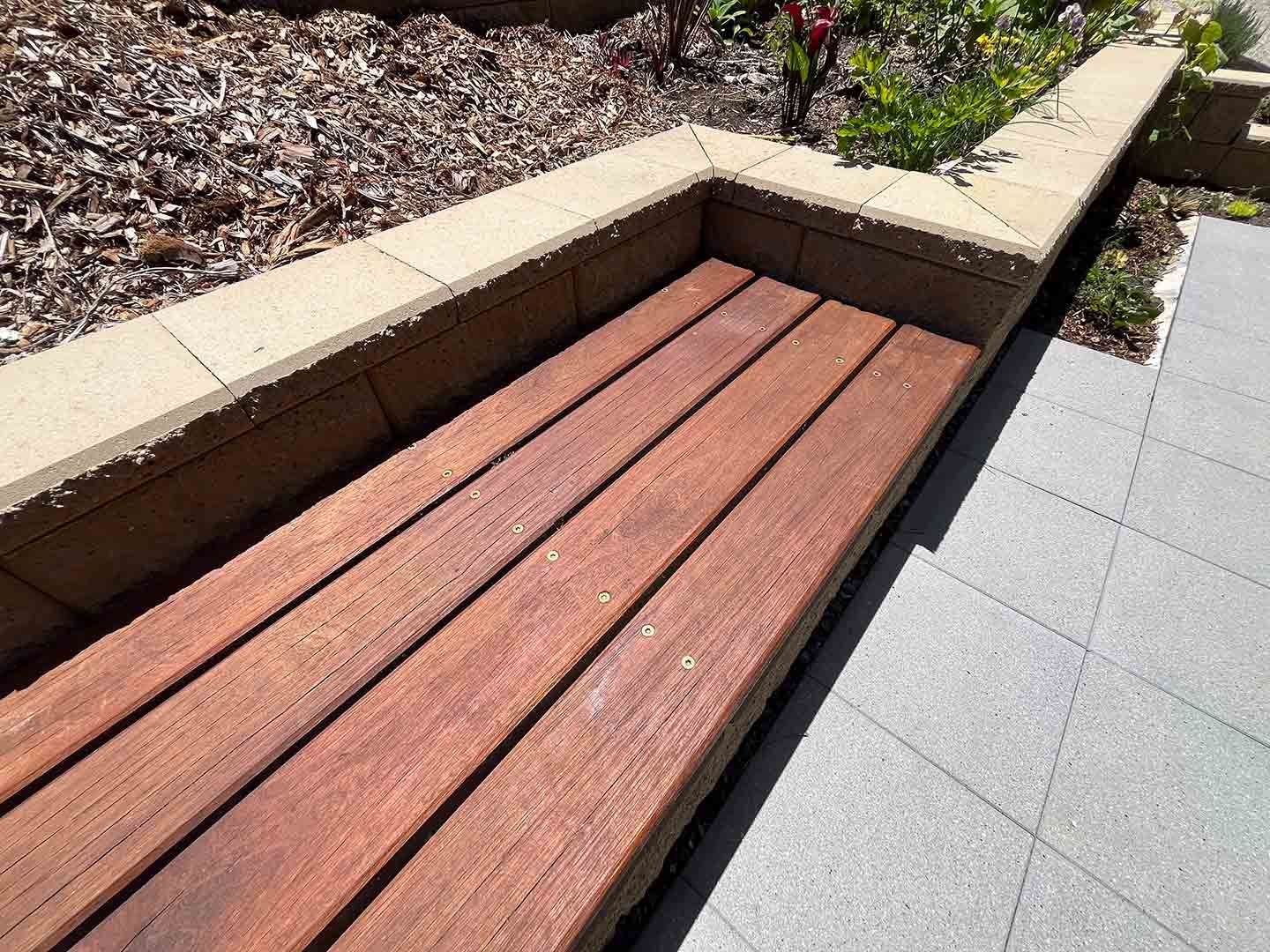 A Wooden Bench Is Sitting Next To A Brick Wall — Gnomes Landscape & Garden Supplies In Old Bar, NSW