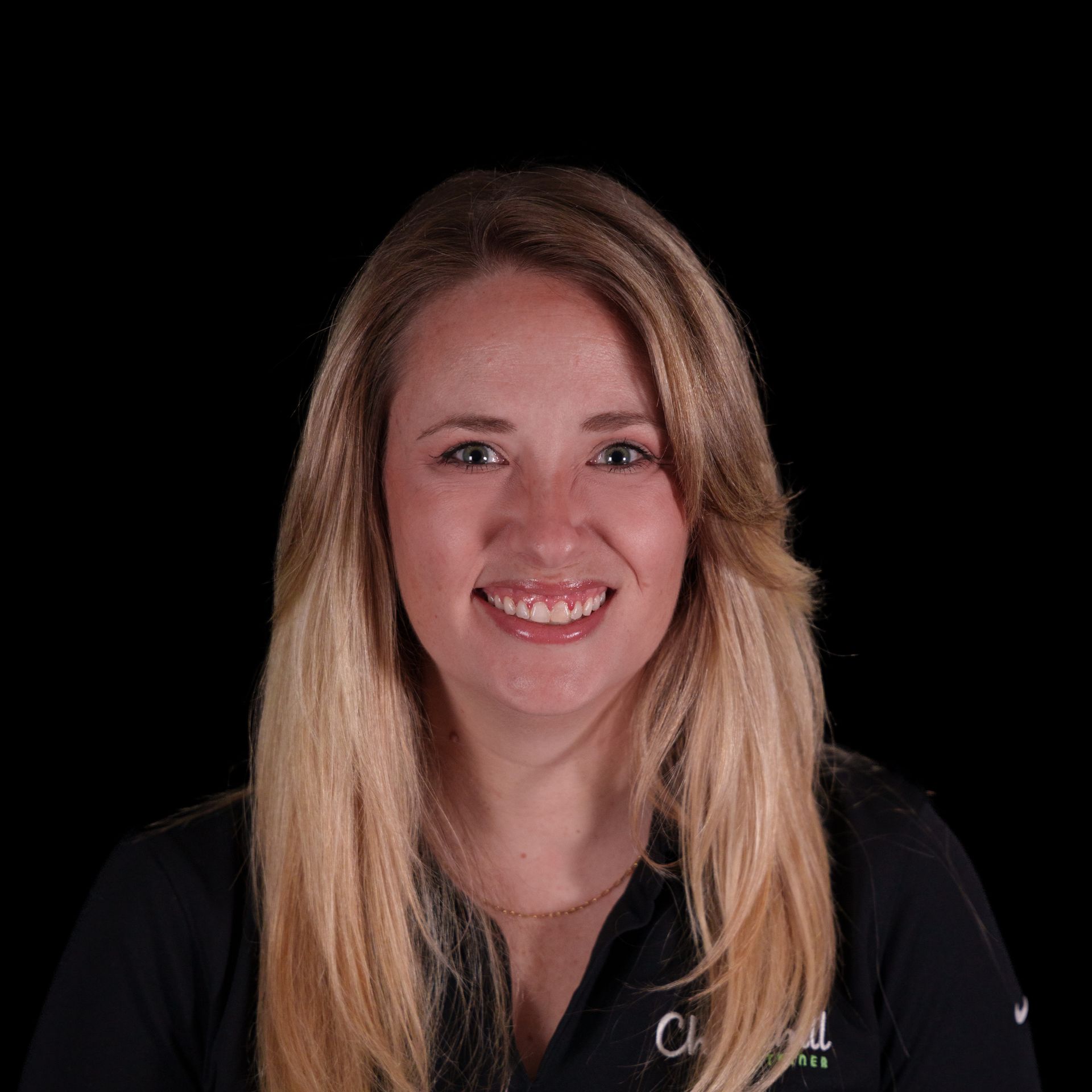Woman with blonde hair smiling, wearing a gray polo shirt with a company logo.