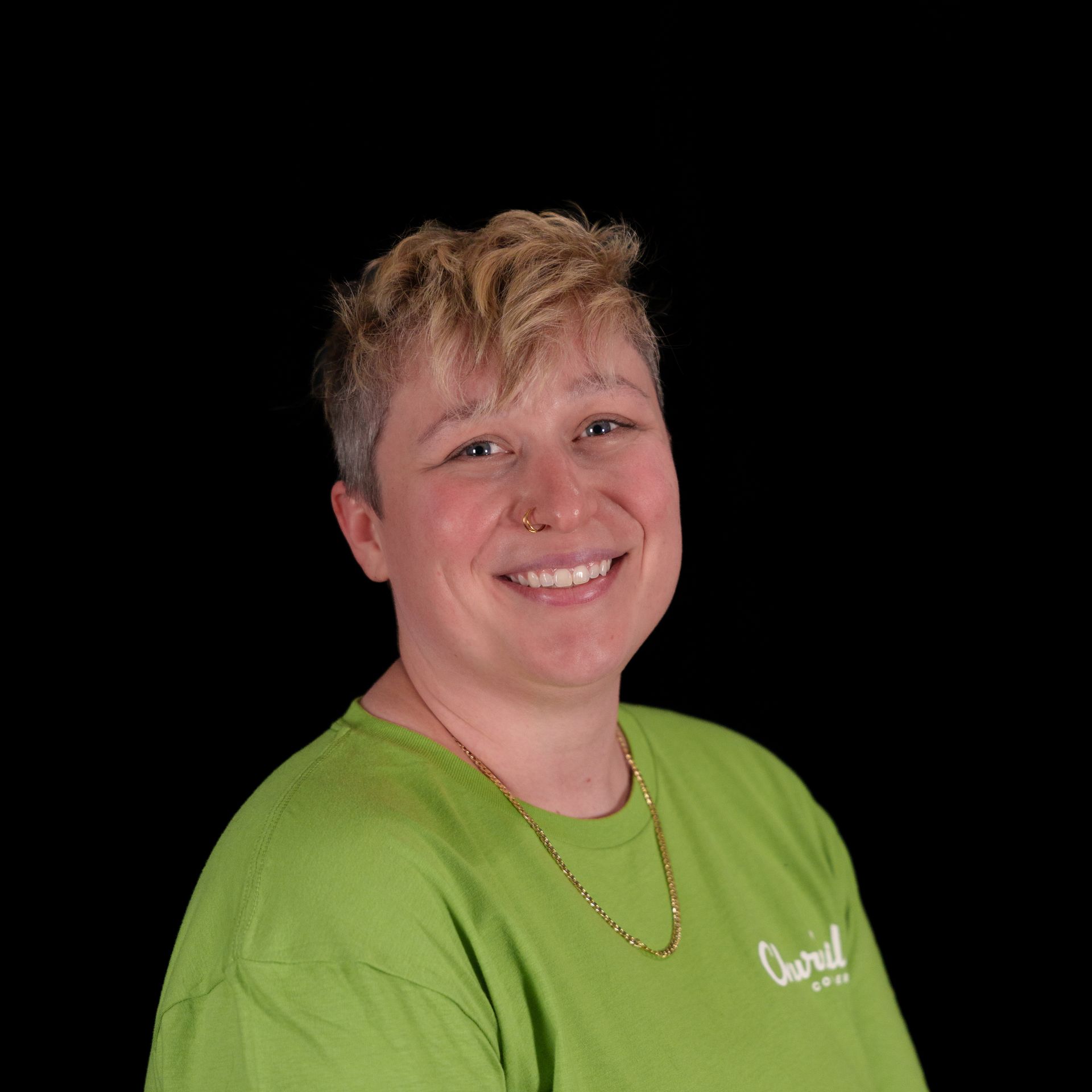 Woman with short blonde hair smiling, wearing a black shirt with 