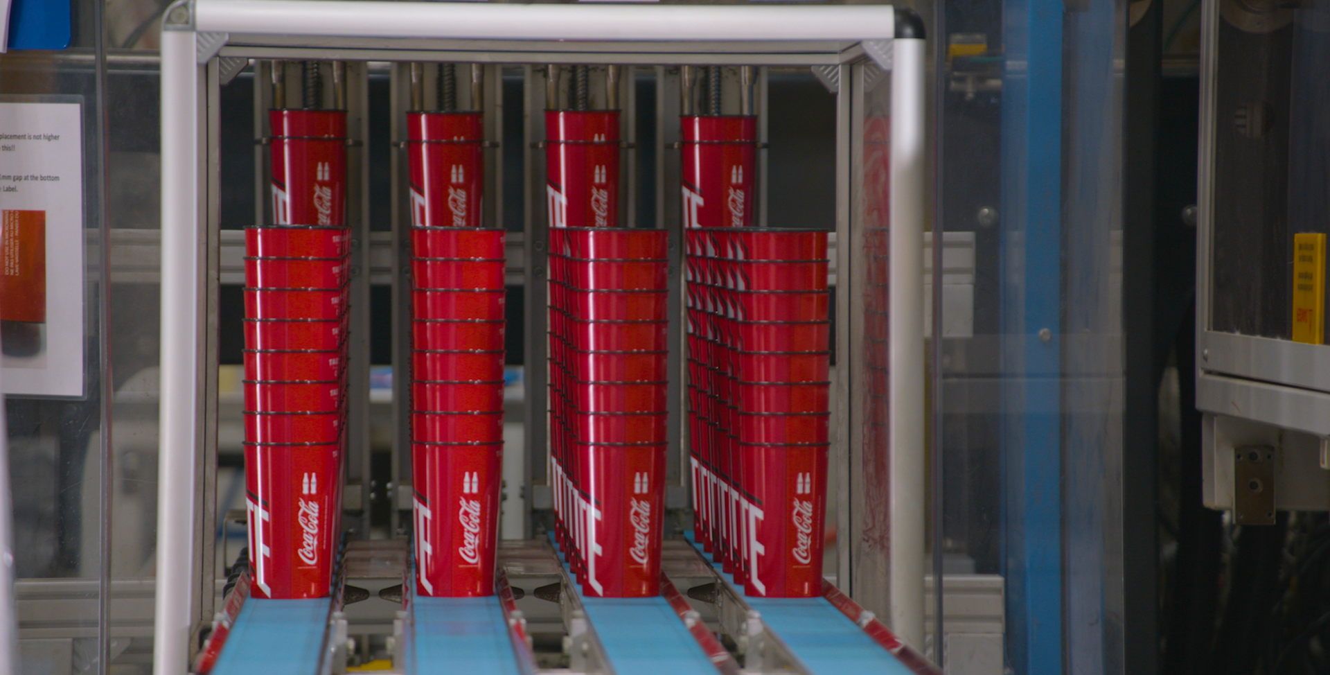 Stacks of red Coca-Cola boxes on a conveyor belt in a factory.