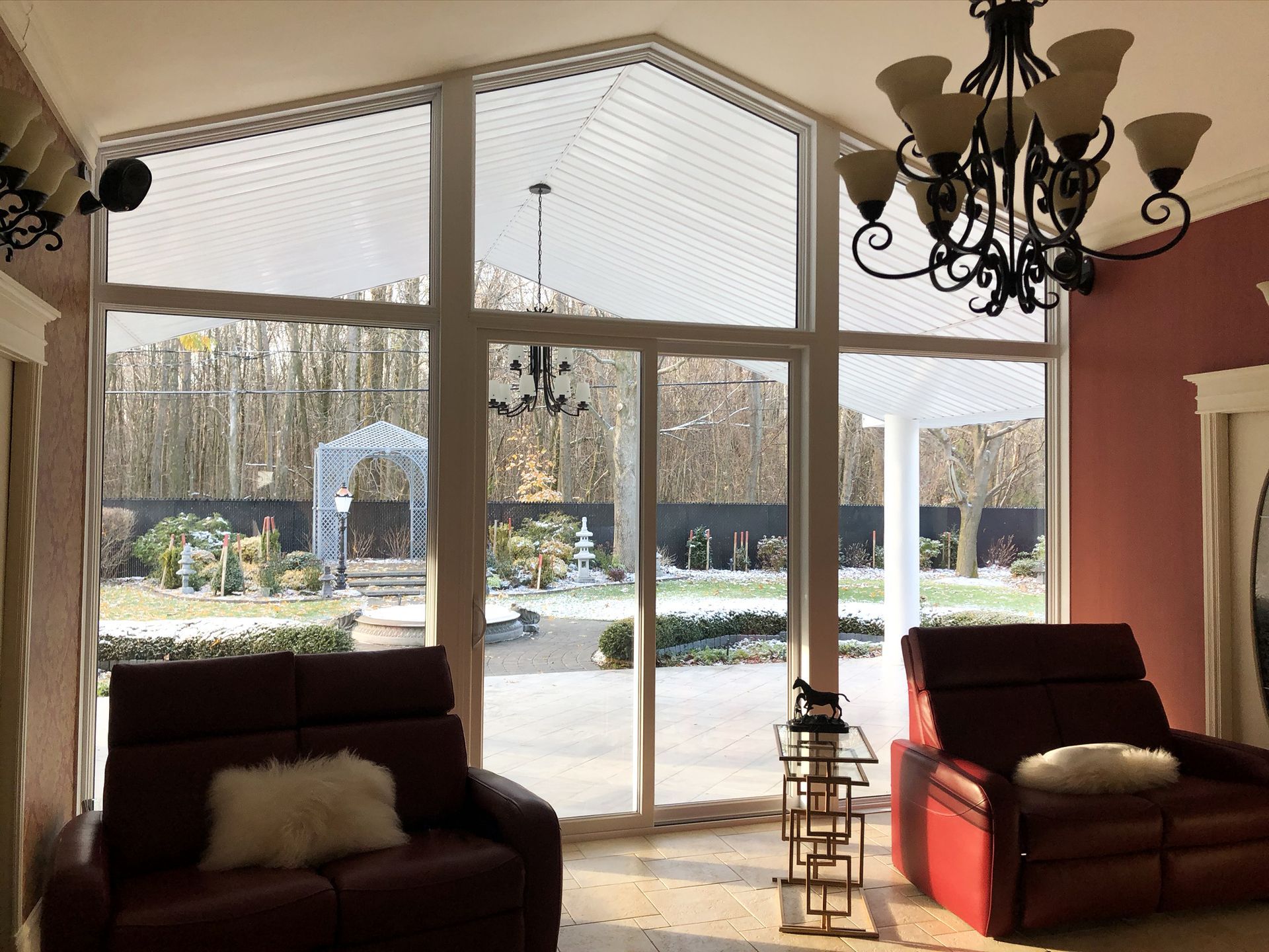 Living room with large windows, red sofas, and a view of a snowy backyard
