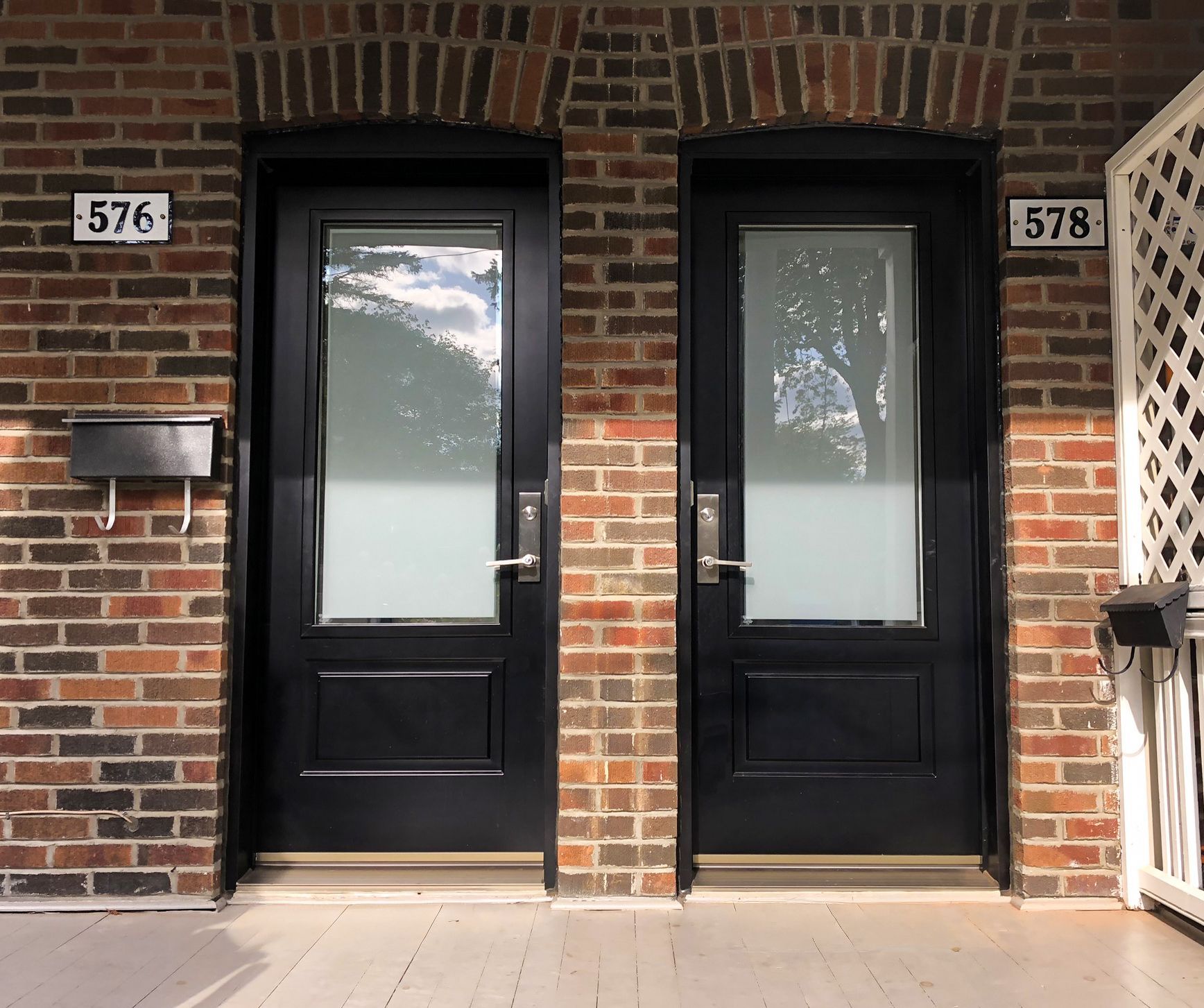 Deux portes d'entrée noires dans un bâtiment en briques, numérotées 576 et 578.