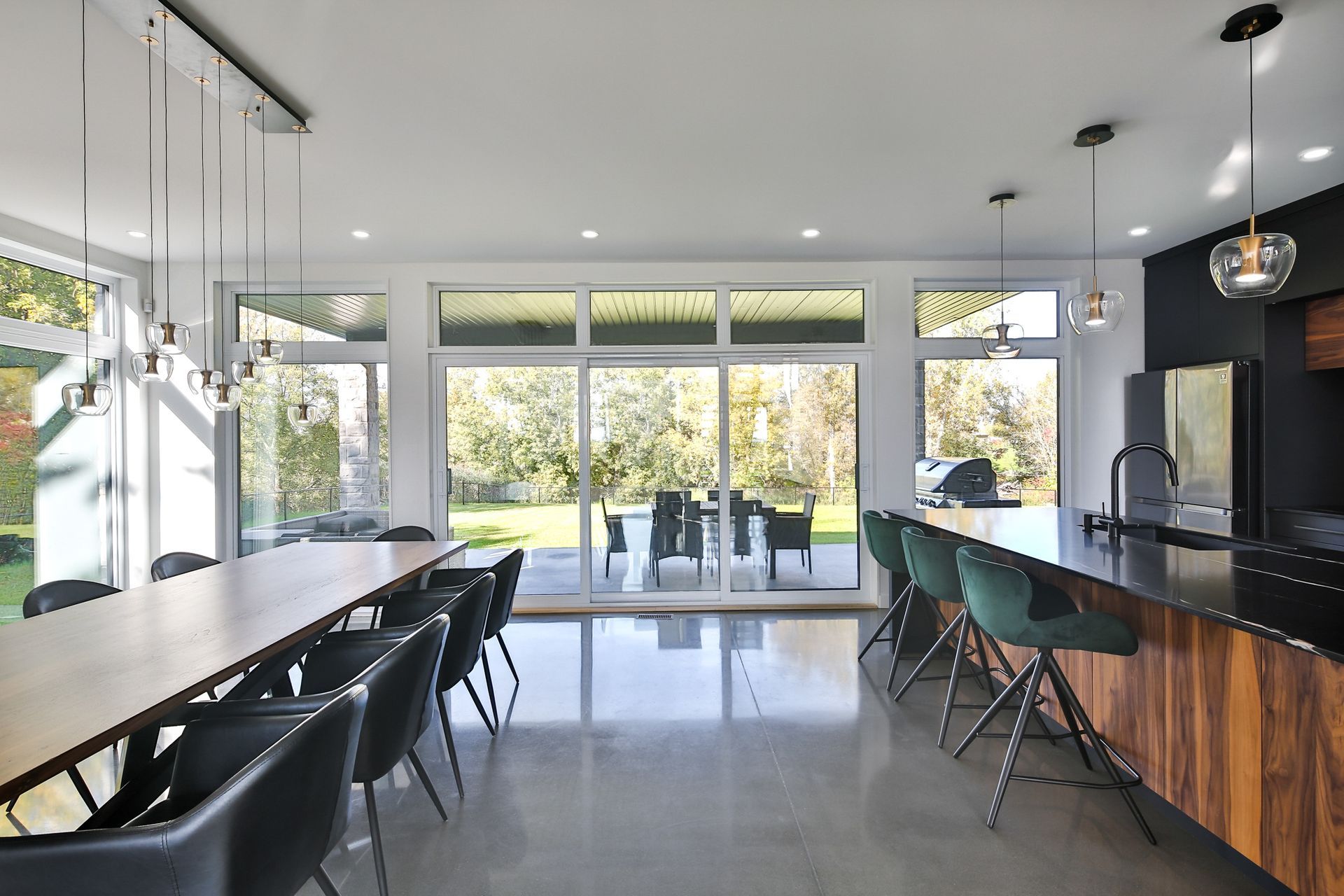 Cuisine et salle à manger modernes à aire ouverte avec de grandes fenêtres, un îlot noir et une vue sur le patio