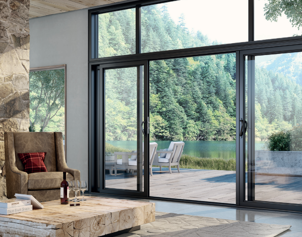 Salon moderne avec portes vitrées du sol au plafond s'ouvrant sur une vue sur la forêt et le lac