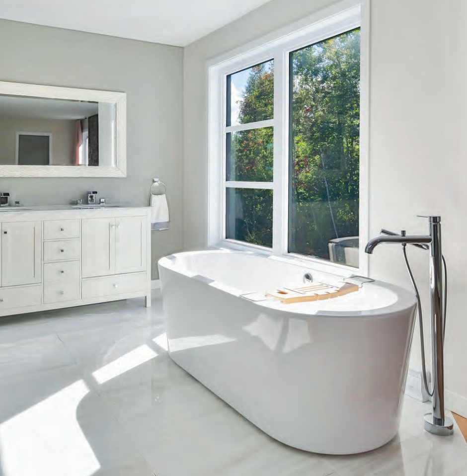 Modern white bathroom with freestanding tub, large window, and vanity mirror