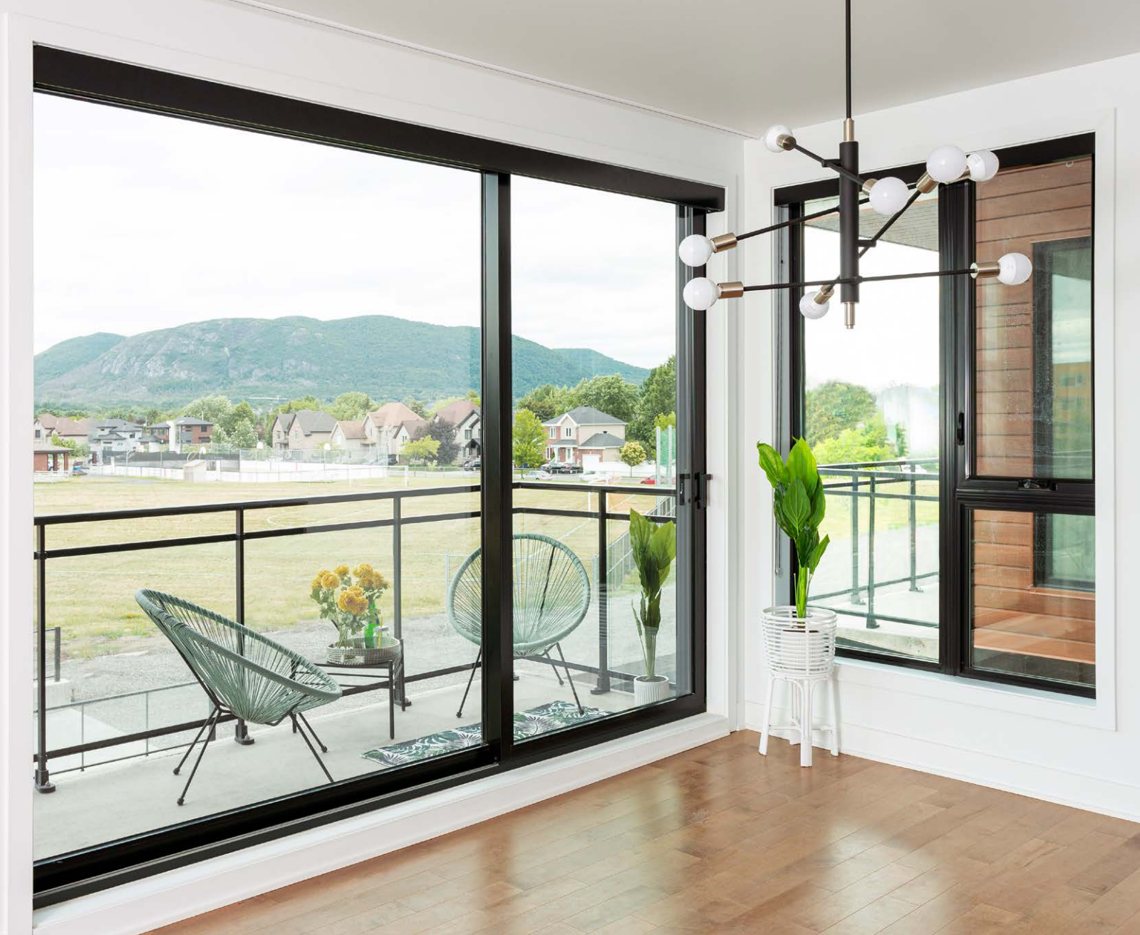 Salon lumineux avec de grandes fenêtres, un balcon et une vue sur la montagne à travers les baies vitrées.