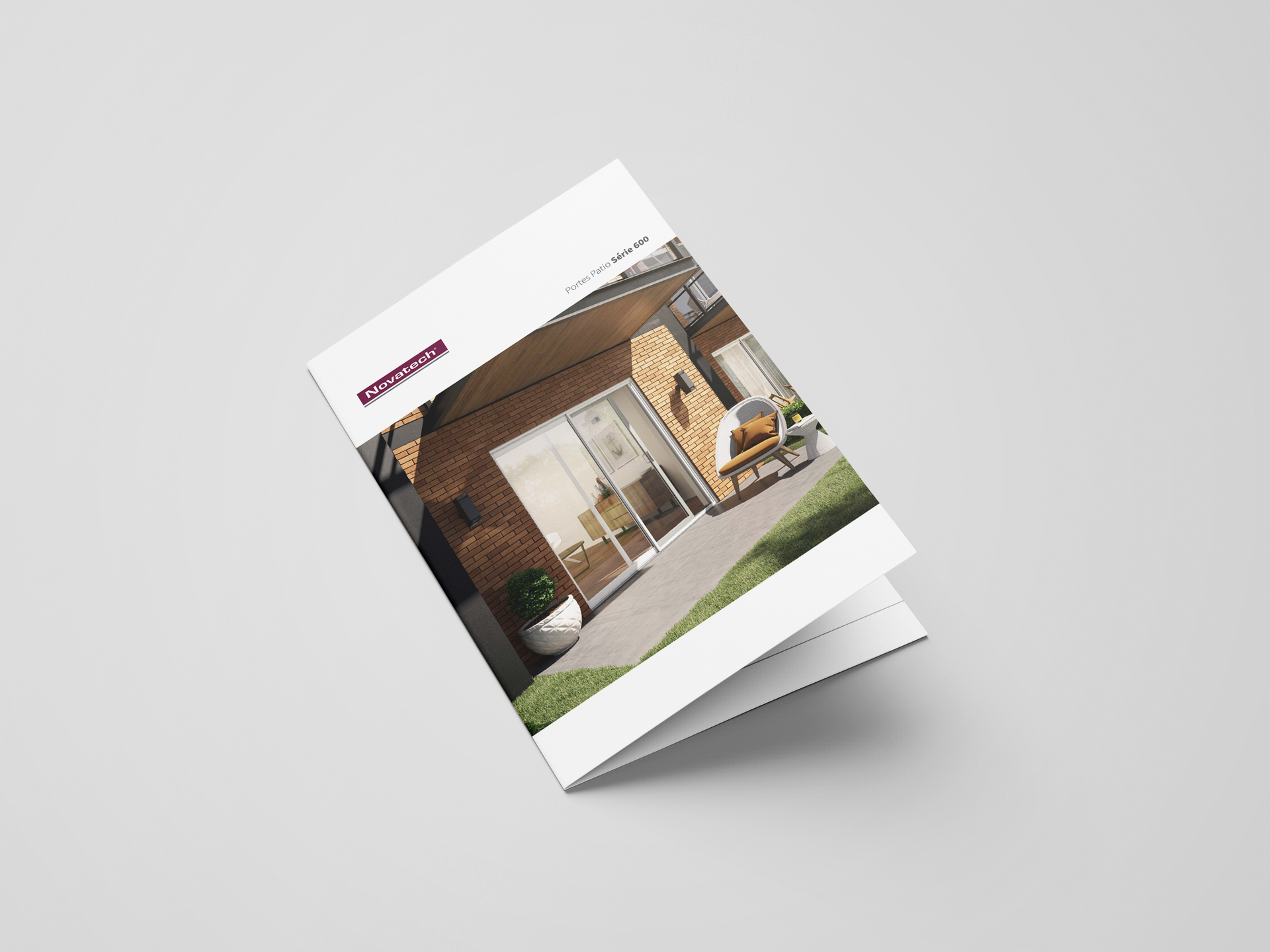 Brochure inclinée sur fond gris montrant l'extérieur d'une maison moderne
