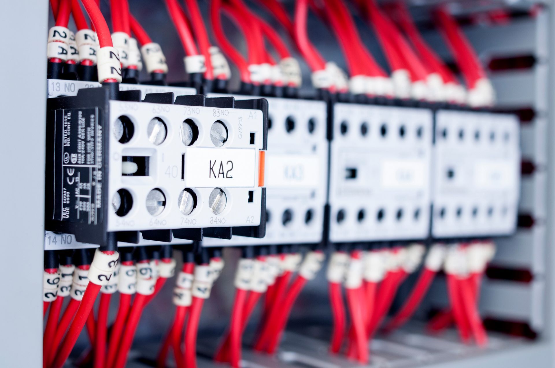 Red wires connected to electrical relays in a panel.