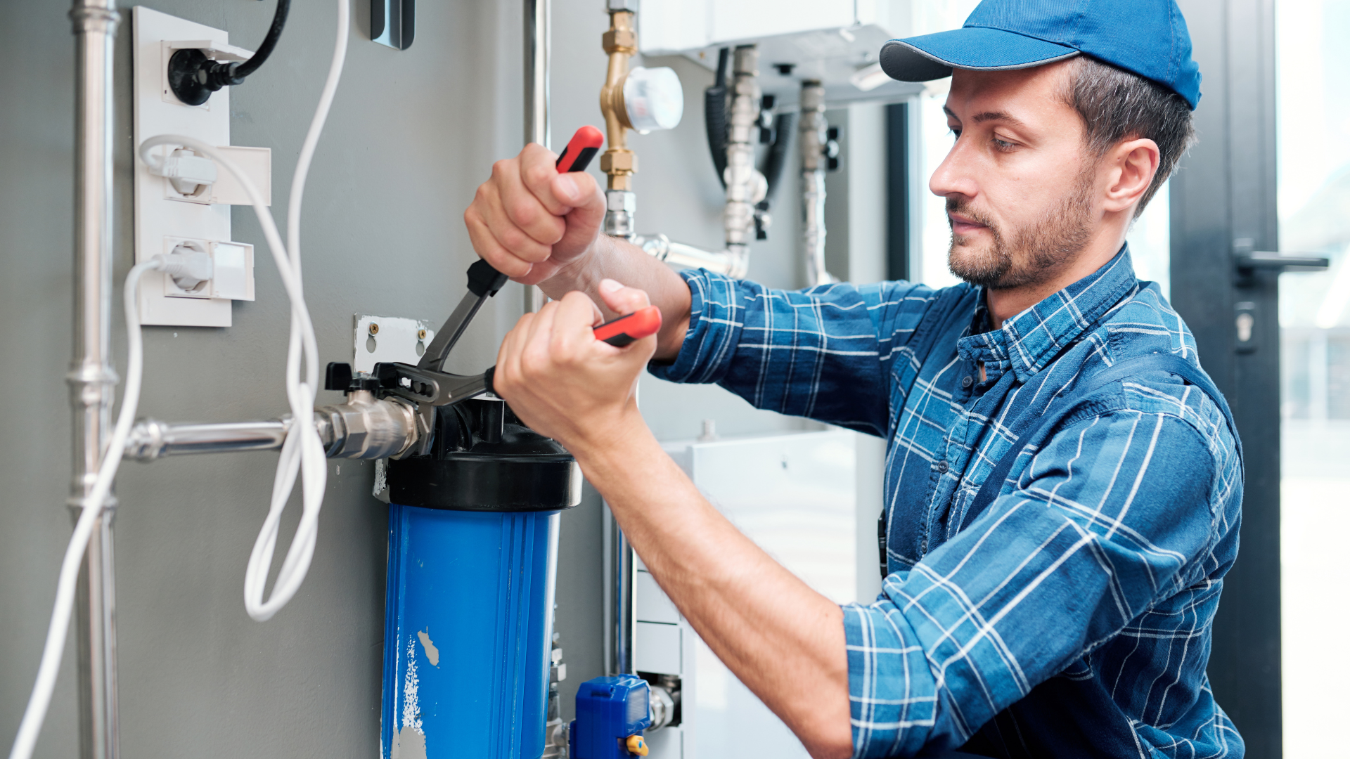 A man is fixing a water filter with a wrench.