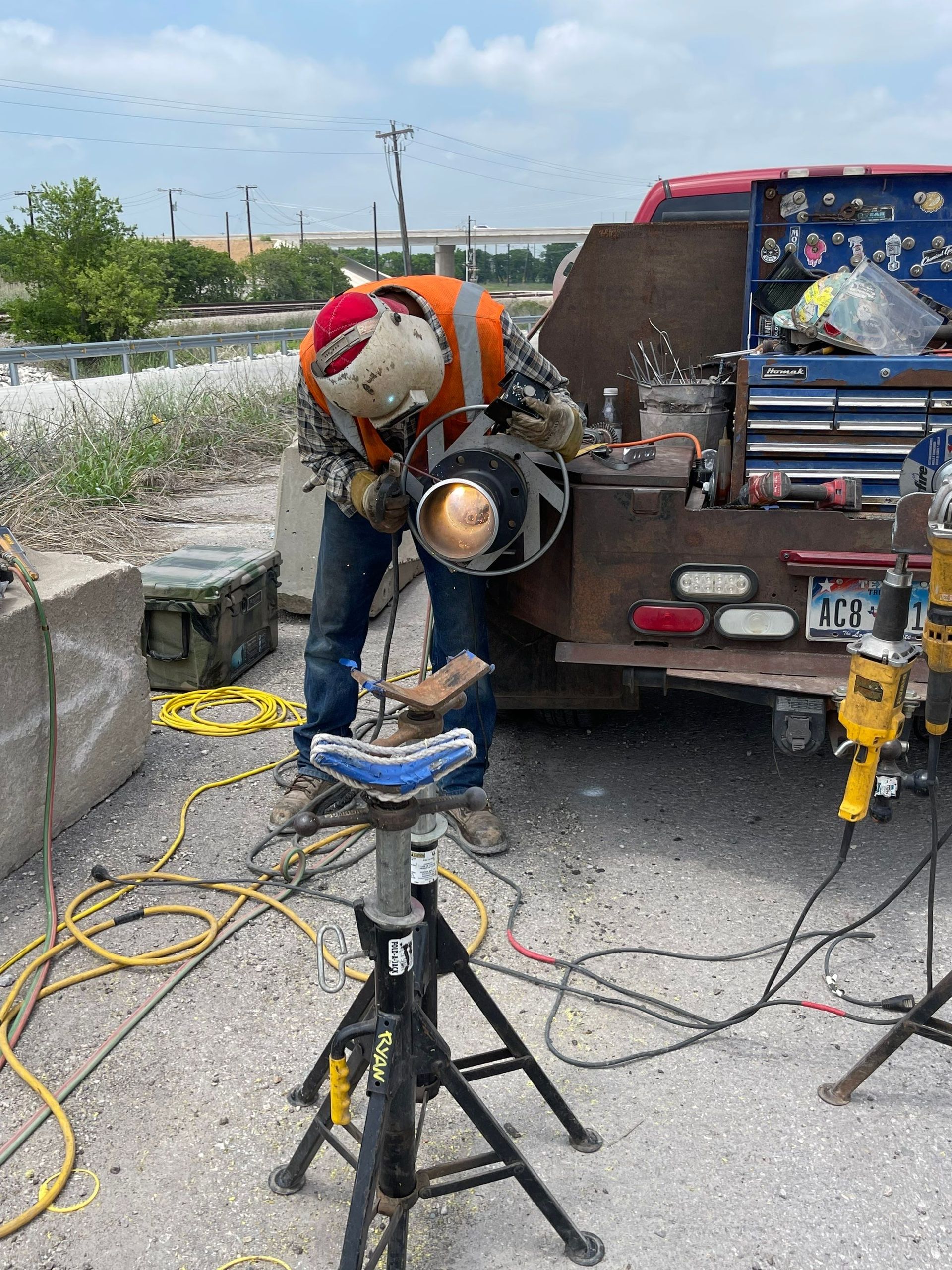 A man is welding a piece of metal in front of a truck.