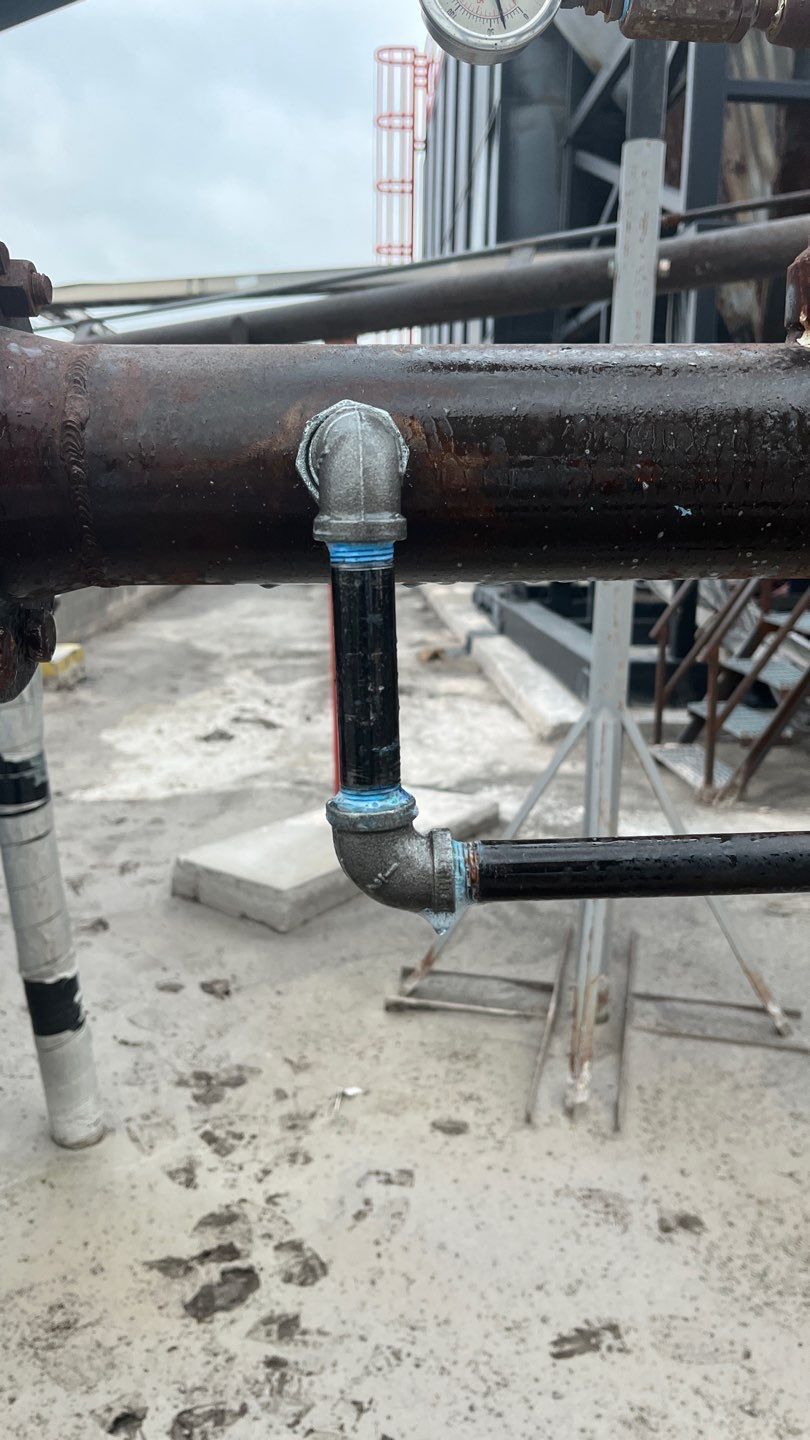 A close up of a pipe with a clock in the background.