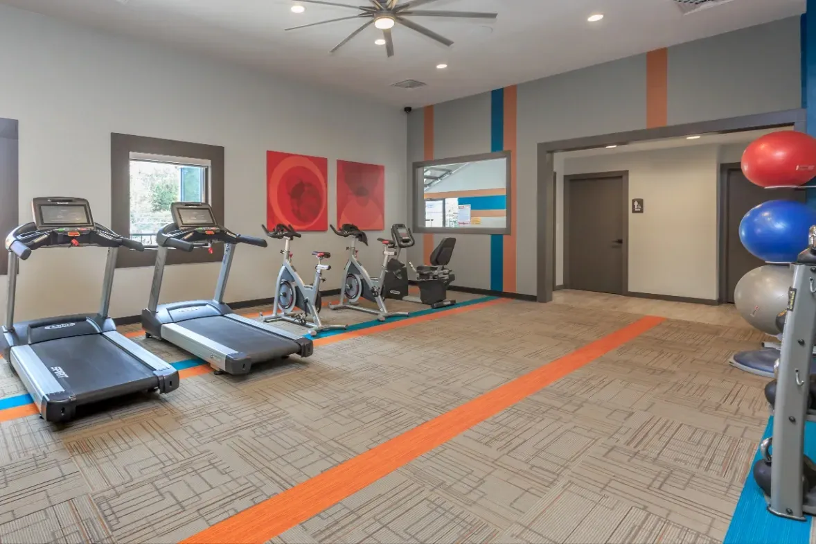 Fitness center with treadmills, stationary bikes, and free weights.