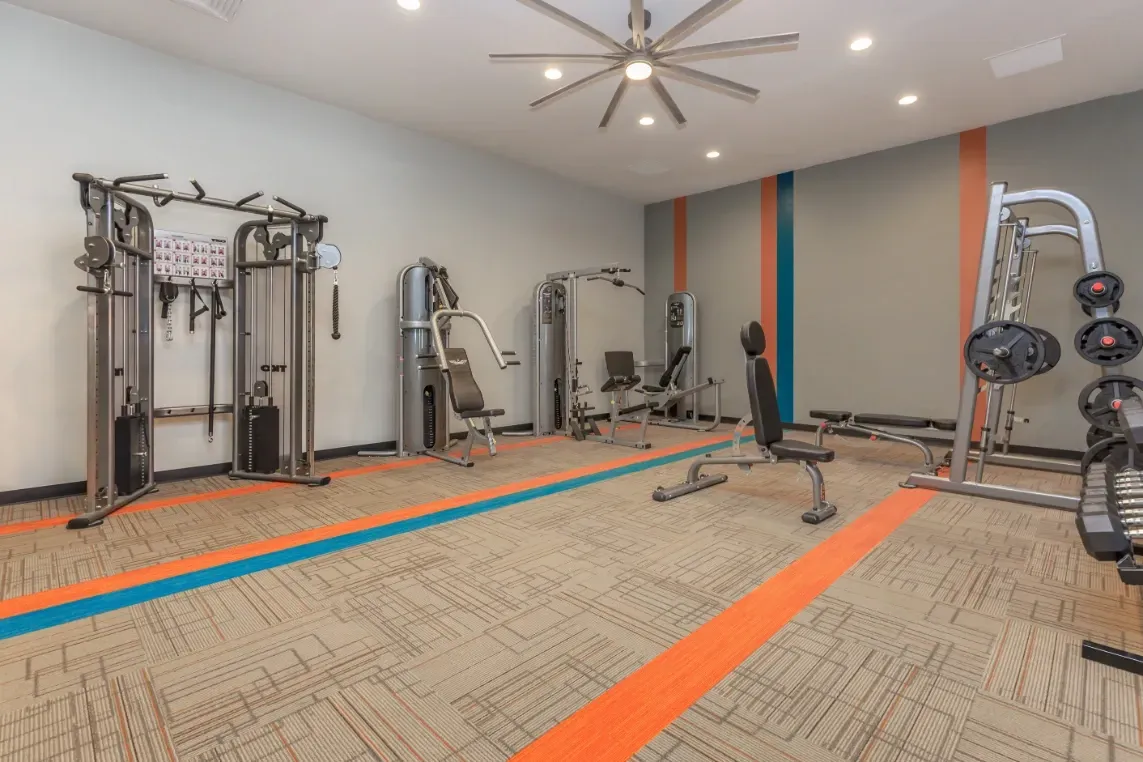 Fitness center with weight machines, cable crossover, and benches.