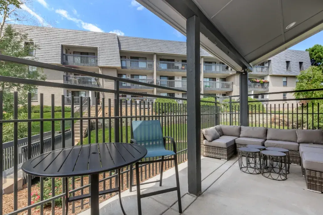 Outdoor patio with seating and table, overlooking apartment buildings.