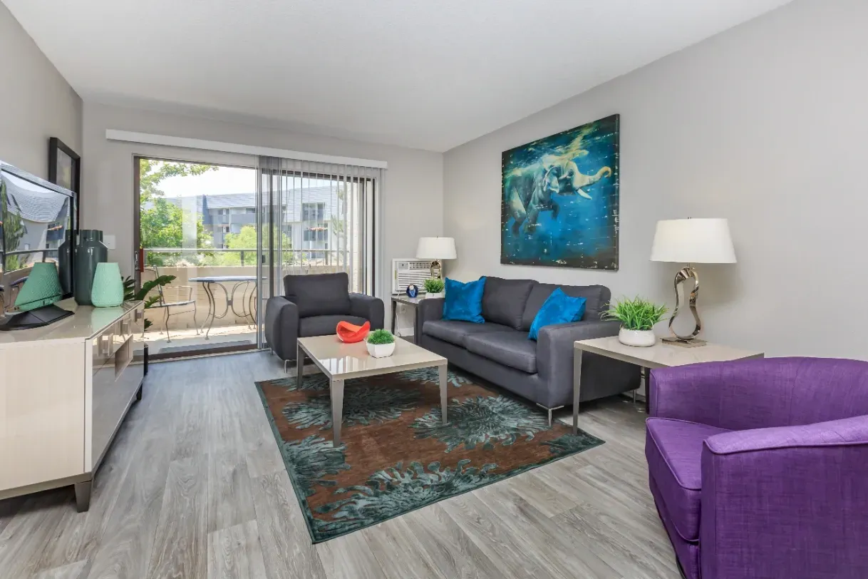 Living room with a sofa, armchair, coffee table, and balcony access.