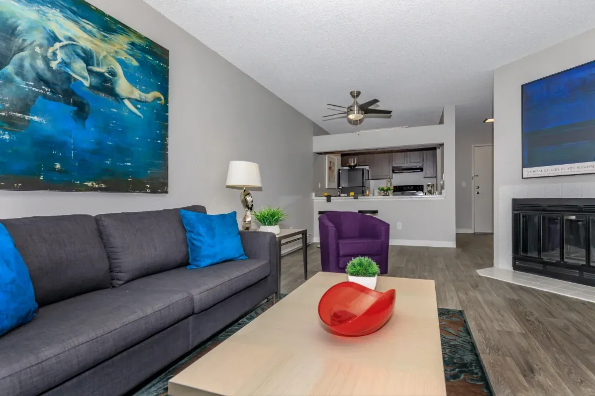 Living room with a charcoal sofa, bright blue accent pillows, a coffee table, and a fireplace.