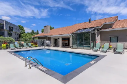 Outdoor swimming pool beside a white building with a red tile roof under a blue sky