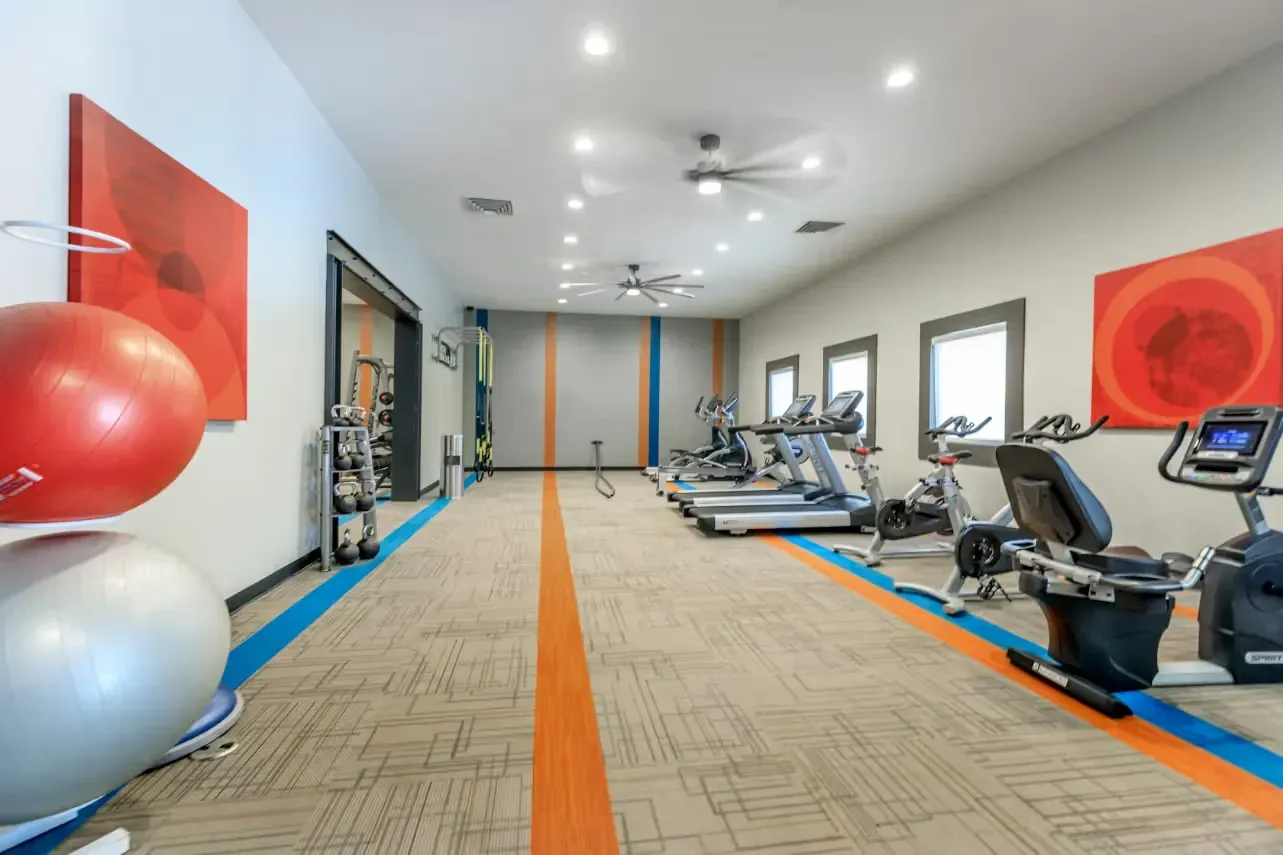 Well-equipped fitness center with treadmills, stationary bikes, weight machines, and exercise balls.
