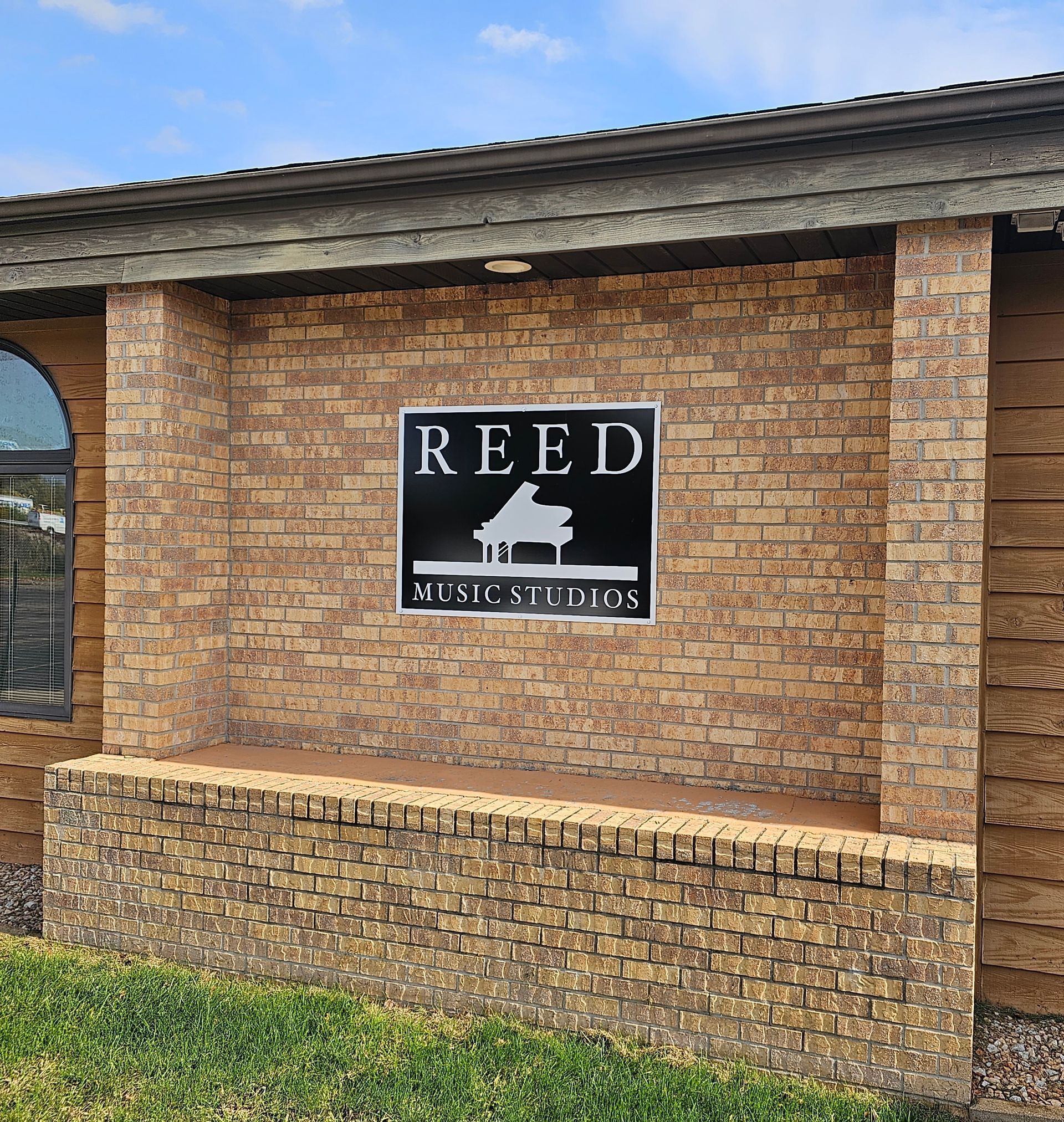 Reed Music Studios sign with piano silhouette on brick building.