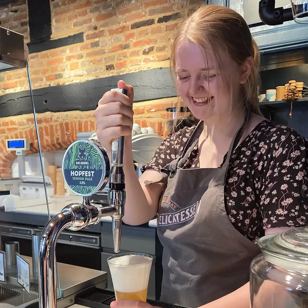 Ellie is pouring a draught beer at French & Day Delicatessen and laughing because it has come out foamy