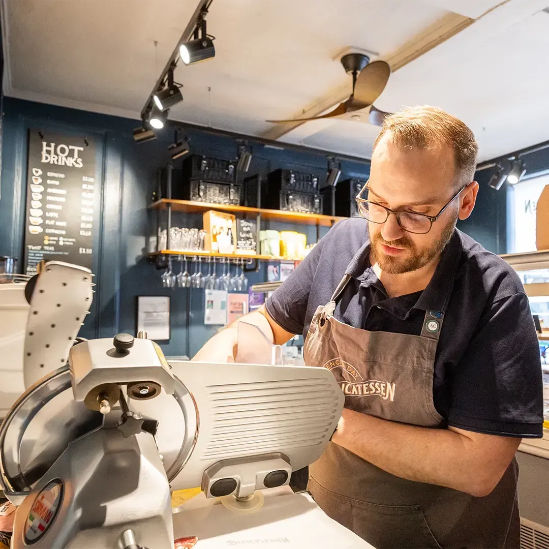 Thomas Day uses a meat slicer at French & Day Delicatessen