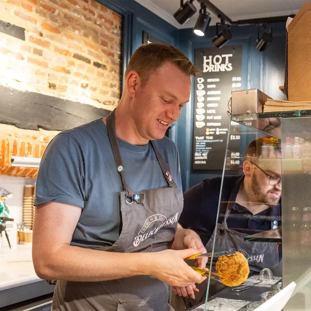 Tom French takes a product out of the counter at French & Day Delicatessen